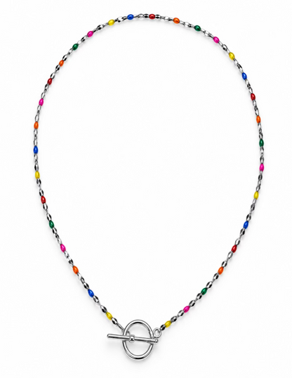 A delicate beaded necklace with a silver toggle clasp, featuring small multicolored beads on a silver chain, displayed on a neutral gray background.
