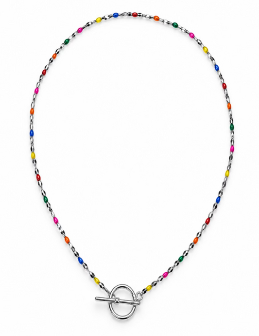 A delicate beaded necklace with a silver toggle clasp, featuring small multicolored beads on a silver chain, displayed on a neutral gray background.